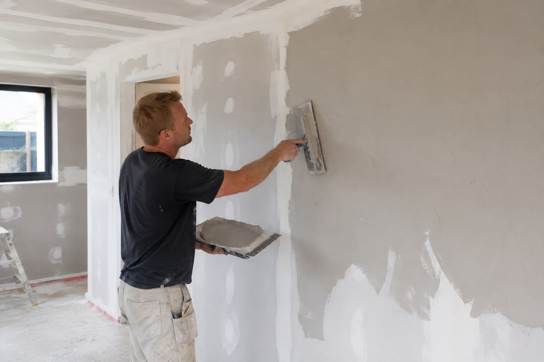Plastering contractor skimming an interior wall smooth in a Wellington home